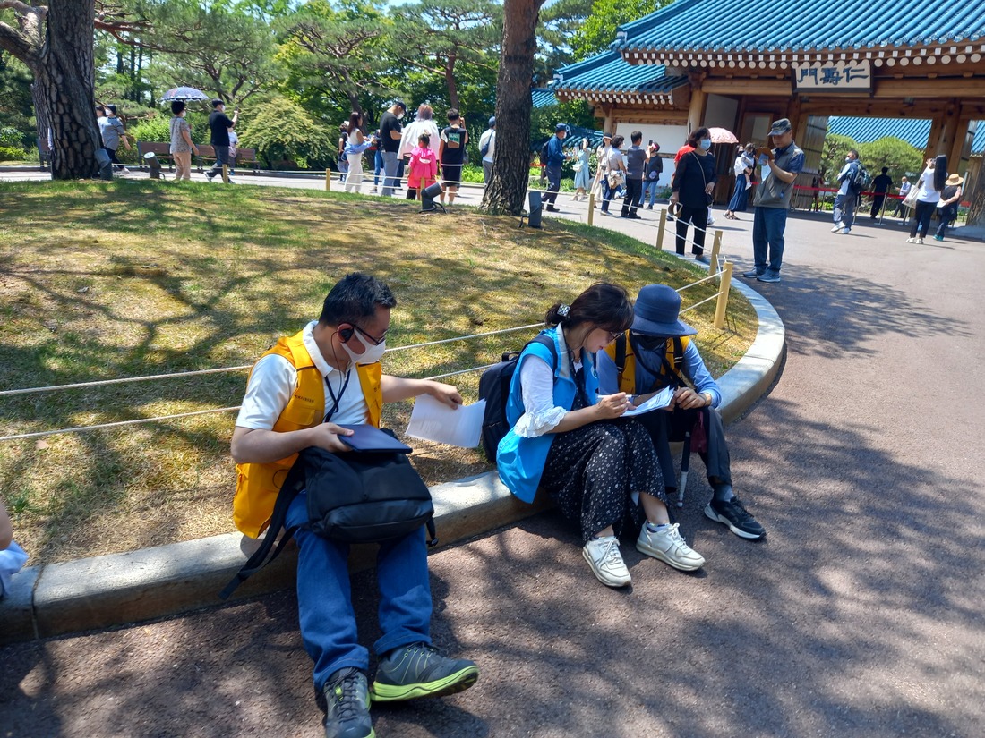인수문 간판이 보이는 인수문 앞 정원에서 만족도 조사를하는 참가자 2인.jpg