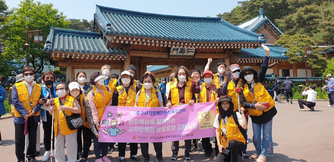 인수문 앞 핑크색 현수막을 들고 노란 조끼를 입고 기념촬영하는 20인의 참가자  .jpg